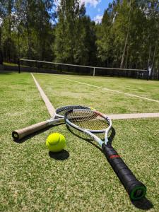 a tennis racket and a tennis ball on a tennis court at Pirties Spa namas in Molėtai