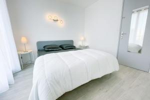 een witte slaapkamer met een wit bed en een spiegel bij The art of living in Grenoble #FV in Saint-Martin-dʼHères