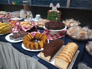 una mesa con diferentes tipos de pasteles y repostería en Stop Inn Cristiano Machado, en Belo Horizonte