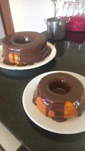 dois donuts cobertos de chocolate em pratos numa mesa em Stop Inn Cristiano Machado em Belo Horizonte
