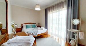 ein Schlafzimmer mit einem Bett und einem großen Fenster in der Unterkunft Casa Gloria in Paço Vedro de Magalhães + 10 Fotos
