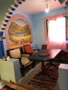 a living room with a table and a painting on the wall at Hostel Meharchen in Chefchaouen