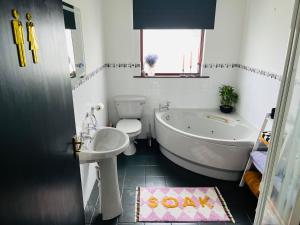 a bathroom with a tub and a toilet and a sink at The Heather Dew in Portstewart +23 photos