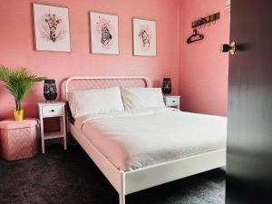 een roze slaapkamer met een wit bed en een roze muur bij The Heather Dew in Portstewart