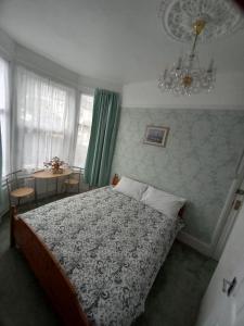 1 dormitorio con cama, mesa y lámpara de araña en Mari London room for holiday, en Ilford