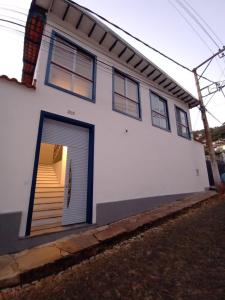 a white house with a garage door and stairs at Casa nova com suítes amplas in Ouro Preto