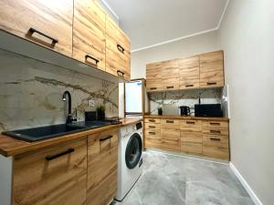 a kitchen with wooden cabinets and a washing machine at MMRent Botanic Room in Gdańsk