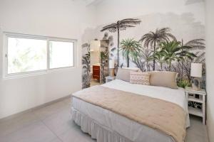a bedroom with a large bed with palm trees on the wall at Puerta Al-Mar Villa in Simpson Bay +30 photos
