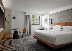 グランドラピッズにあるSheraton Grand Rapids Airport Hotelのベッドとテーブルが備わるホテルルームです。