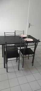 mesa de comedor y sillas con mesa negra y sillas en Chez Fred, en Mordelles