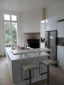 een witte keuken met een wastafel en een koelkast bij Bed & Breakfast à 20mn direct St Lazare en Train in Sannois