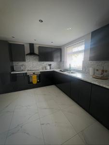 a kitchen with black cabinets and a white tile floor at Modern 4 Bed - 10 mins to centre in Liverpool