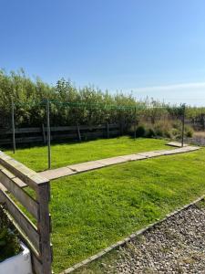 un parque con una valla de madera y césped verde en Tangles & Kelpie, en Burray Village