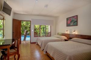 um quarto com 3 camas, uma secretária e janelas em Hotel Boyeros em Liberia