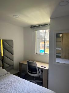 1 dormitorio con escritorio, 1 cama y ventana en Habitación en apartamento Robledo-Medellin, en Medellín