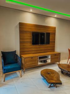 ein Wohnzimmer mit einem TV, einem Stuhl und einem Tisch in der Unterkunft Chill House Praia do Preá-CE in Prea