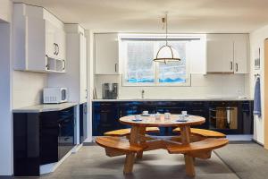 a kitchen with a wooden table and a table and bench at Elfe-Apartments FerienMietWohnungen in Emmetten