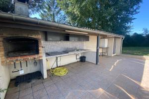 a backyard patio with a kitchen and a stove at La Graviere - 28pers - swimming pool pétanque billiards in Fontenay-Trésigny