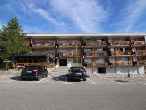 two cars parked in a parking lot in front of a building at Appartement cosy avec balcon, 6 pers, proche pistes et commerces, Huez - FR-1-405-199 in LʼHuez