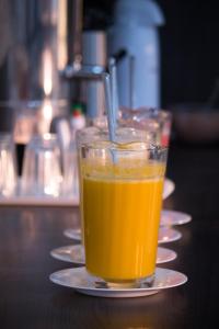 a glass of orange juice on a plate on a table at Maper Park Carajás in Parauapebas
