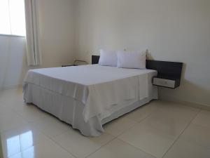 ein Schlafzimmer mit einem großen Bett mit weißer Bettwäsche und Kissen in der Unterkunft Maper Park Carajás in Parauapebas