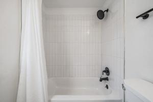 a white bathroom with a tub and a shower curtain at Satoshi Hideout Park Studios in St Petersburg