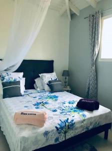 - une chambre avec un grand lit orné de fleurs bleues dans l'établissement Biscuit - Gîte du moulin, à Petit-Canal