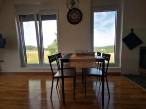 ein Esstisch mit Stühlen und einer Uhr an der Wand in der Unterkunft Apartman 982 Divčibare in Divčibare