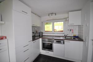 a kitchen with white cabinets and a sink and a window at Ferienhaus Schneekopf in Suhl