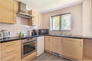 a large kitchen with wooden cabinets and a sink at Lovely 2bed Apt in Redditch, Free Wi-Fi & Parking in Redditch