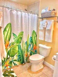 a bathroom with a toilet and a tropical shower curtain at Private Guest House in Miami
