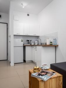 a kitchen with white cabinets and a wooden table at Apartament Kasprzaka Bliska Wola in Warsaw