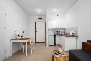 a living room with a table and a kitchen at Apartament Kasprzaka Bliska Wola in Warsaw