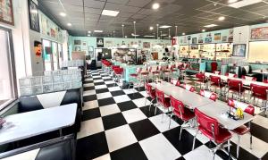 ein Restaurant mit roten Stühlen und Tischen und einem karierten Boden in der Unterkunft MCM Retro Beachfront Studio Great View, King Bed Remodeled in Daytona Beach