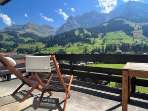 a rocking chair on a balcony with a view of a mountain at Schönes 2-Zimmer Studio mit grossem Balkon und Bergpanorama - 400m von Talstation Sillerenbahn in Adelboden