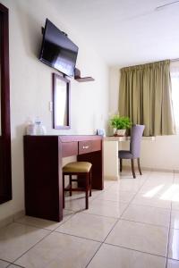 een woonkamer met een bureau en een tv aan de muur bij Hotel Acuario in Ocotlán
