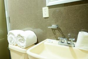 a bathroom with a sink and a toilet with towels at Hotel Acuario in Ocotlán