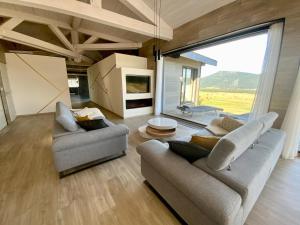 una sala de estar con 2 sofás y una ventana grande en Artik chalet avec vue à 180 degrés et piscine, en Les Angles
