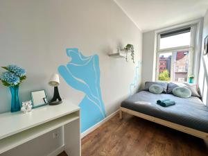 a bedroom with a bed with a blue painting on the wall at MMRent Lady Blue Room in Gdańsk