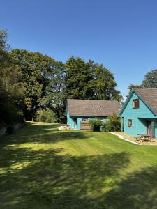 niebieski dom na trawniku z drzewami w tle w obiekcie Foxglove Cottages w mieście Drymen