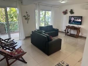 a living room with a couch and a tv at BELÍSSIMA CASA ILHABELA in Ilhabela