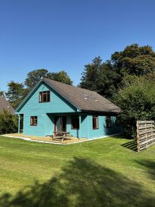 a blue house with a picnic table in a yard at Foxglove Cottages in Drymen