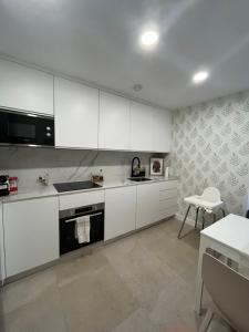a white kitchen with white cabinets and a table at Casa con vistas y piscina privada in Málaga