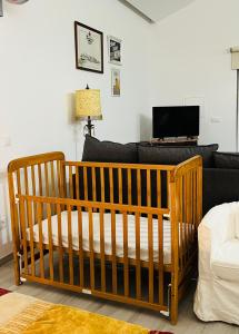 łóżeczko dziecięce w pokoju z kanapą i telewizorem w obiekcie Mike’s House w mieście Lourinhã