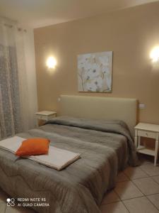 a bedroom with a bed with an orange pillow on it at Residenza Il Rivo in Rivotorto