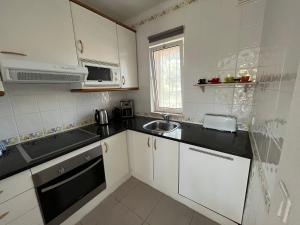 Una pequeña cocina con gabinetes blancos y un fregadero. en House´s Golf, en Almancil