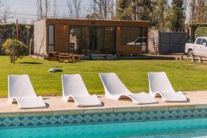 eine Reihe weißer Stühle neben einem Pool in der Unterkunft Tiny House in Mendoza