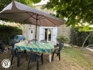 a table and chairs with an umbrella in a yard at Gîte Thiré, 4 pièces, 5 personnes - FR-1-426-396 in Thiré