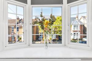 un jarrón de flores sentado en un alféizar de la ventana en Modern Two Bedroom Apartment with Free Parking!, en Londres