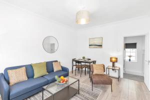 uma sala de estar com um sofá azul e uma mesa em Modern Two Bedroom Apartment with Free Parking! em Londres